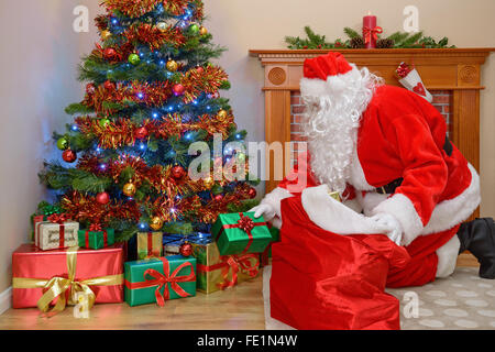 Santa Claus liefert Geschenke zu einem Haus und nehmen Geschenke von seinen sack Stockfoto