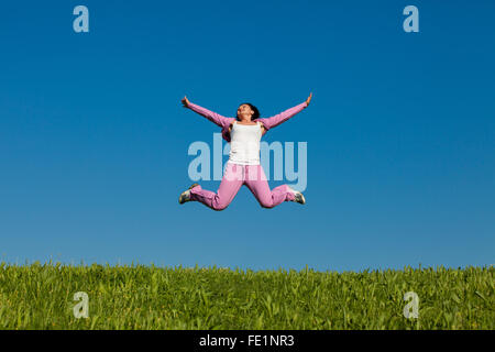 hübsche junge Frau, die auf dem grünen Rasen springen Stockfoto