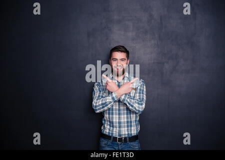 Lächelnd legerer Mann zeigenden Finger Weg über schwarzen Hintergrund Stockfoto