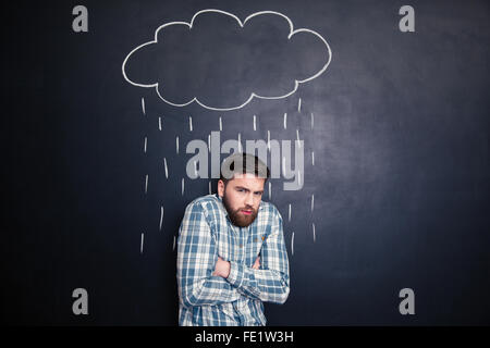 Hübscher bärtigen Mann Kältegefühl stehen unter dem Regen auf Hintergrund der Tafel gezeichnet Stockfoto