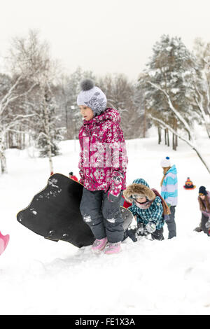 UFA - Russland 16. Januar 2016 - Kinder genießen den frischen Schnee mit improvisierten Folien und Schlitten hinunter Schnee Banken in Stockfoto