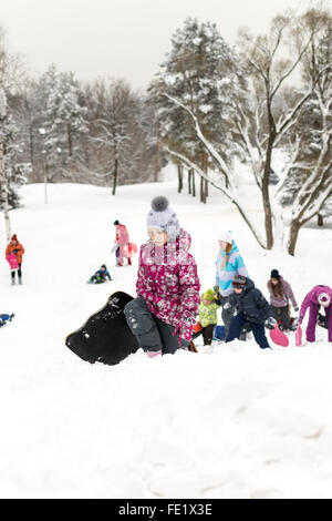 UFA - Russland 16. Januar 2016 - Kinder genießen den frischen Schnee mit improvisierten Folien und Schlitten hinunter Schnee Banken in Stockfoto