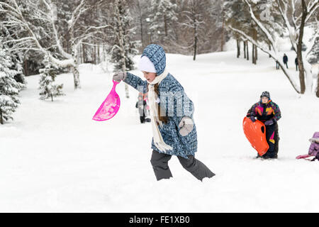 UFA - Russland 16. Januar 2016 - Kinder genießen den frischen Schnee mit improvisierten Folien und Schlitten hinunter Schnee Banken in Stockfoto