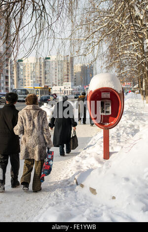 Fußgänger gehen Vergangenheit ein alternden sowjetischen Stil öffentlichen Anruf box im Winter von Januar Stockfoto