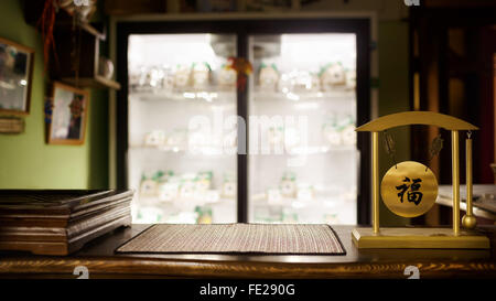 Tee-Shop unscharf Hintergrund, Holzbar, Tischplatte. Traditionelle Zeremonie, Gong mit chinesischen Schriftzeichen wünschen Glück. Beleuchtete Vitrine, Textfreiraum. Stockfoto