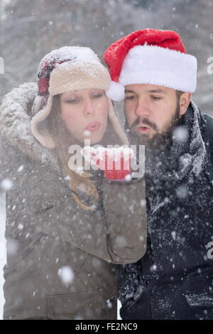 bärtigen Kerl und hübsches Mädchen Schneetreiben aus ihrer Hand im freien Stockfoto