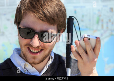 Junger blinder Mann mit Stock mit assistiver Technologie Stockfoto