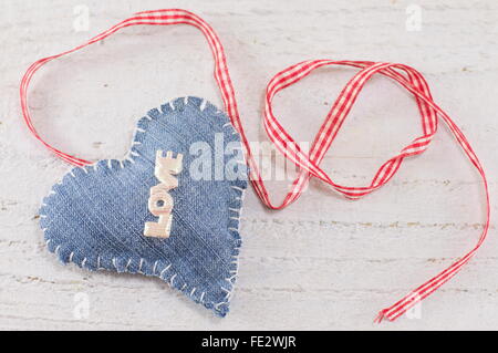 Denim-Herz mit dem Wort Liebe drauf gelegt auf eine hölzerne Tafel Stockfoto