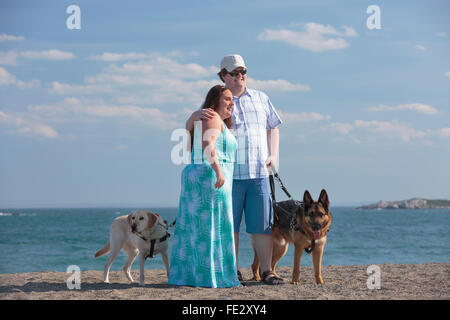 Junges Paar mit Sehbehinderungen und Service-Hunde am Strand Stockfoto