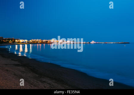 Nacht szenische Ansicht der verlassene Strand, Seeküste und leuchtende Benalmadena entfernt. Ruhiges Meer, tiefblaue Meerwasser und Himmel. Spanien. Stockfoto