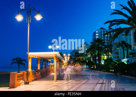 Landschaft Nacht Ansicht der menschenleer Böschung in Benalmadena Stadt, Andalusien, Spanien. Weißer Marmor Wanderweg, leuchtende Laternen, palm Stockfoto