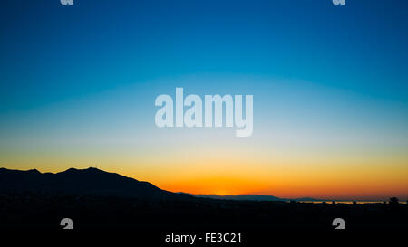 Panoramablick über dunkle Silhouette der Berge auf bunten Sonnenaufgang Himmelshintergrund Stockfoto