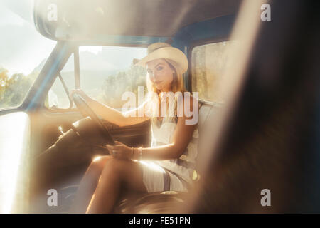 Porträt von einer attraktiven jungen Frau mit Hut Autofahren auf sonnigen Tag Stockfoto