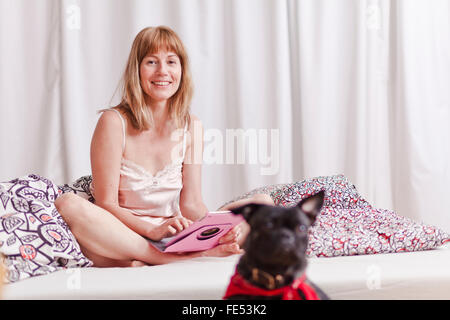 Frau im Bett mit einem niedlichen Hund entspannende. Stockfoto