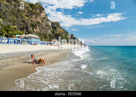 Frau im Liegestuhl in der Brandung auf Mingardo Strand an der mediterranen Küste des Cilento, Kampanian, Italien Stockfoto