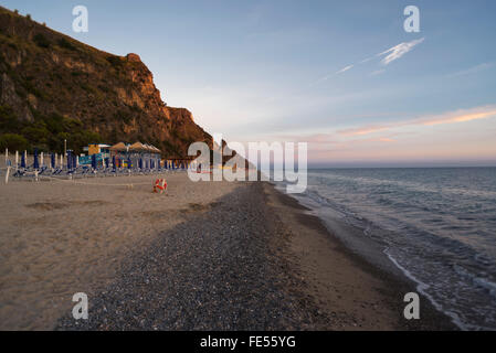 Liegestühle, Strandbäder und Sonnenschirme am Strand Mingardo an der Mittelmeerküste im Cilento im letzten Sonnenlicht, Kampanien, Italien Stockfoto