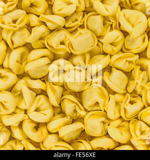 Tortellini Emiliani hausgemachte italienische rohe Makkaroni Nudeln gefüllt mit Rind- und Schweinefleisch Fleisch Textur Hintergrundmuster Stockfoto