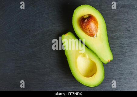 Avocadoscheiben auf einem schwarzen Schiefer, reif Stockfoto