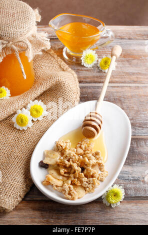 Müsli mit Honig und getrocknete Früchte. Glas Honig im Hintergrund. Stockfoto