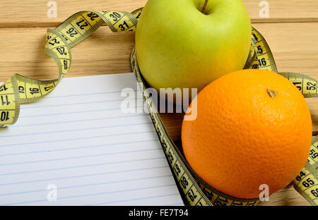 Notebook mit Apfel und Orange Früchte auf Tisch Stockfoto