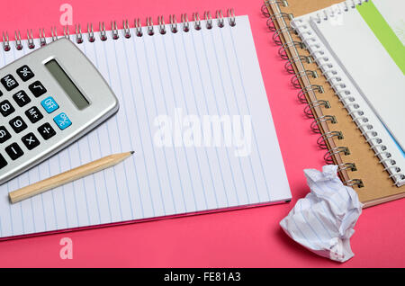 Notebook mit Taschenrechner auf rosa Hintergrund Stockfoto