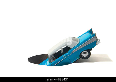 Studioaufnahme von einem Spielzeug-Auto in ein Loch stecken Stockfoto