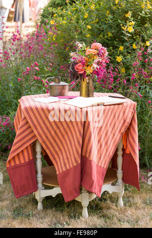 Antiken Tisch mit Gästebuch und Blumen im Garten zu einem zwanglosen Outdoor Landhausstil Hochzeit. Schöne shabby chic Sommer Hochzeit Dekorationen. Stockfoto