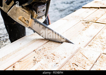 Ein Arbeiter mit einer Kettensäge Holz Stockfoto