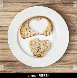 Wheaten Brot in Herzform auf der weißen Platte geschnitten. Zum Valentinstag. Kreative Küche. Stockfoto