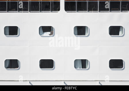 Nahaufnahme von Kabinenfenster in Reihen bilden ein Muster auf den weißen Rumpf von einem Kreuzfahrtschiff im Hafen von Rostock, Deutschland Stockfoto