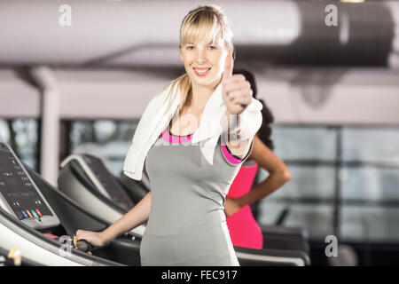 Lächelnde Frau auf Laufband Daumen auftauchen Stockfoto