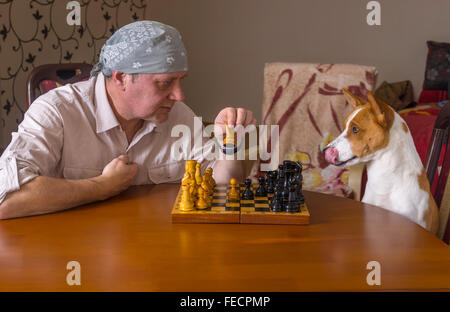 Junger Hund und reifer Mann spielt Schach in einem Familien-Turnier Stockfoto