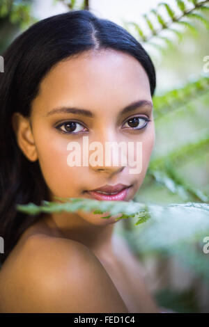Porträt von einer hübschen Frau auf der Suche durch Blätter Stockfoto