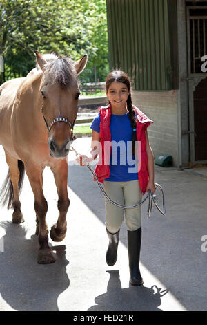 Kleine Mädchen zu Fuß ihr Lieblings Pony außerhalb Stockfoto