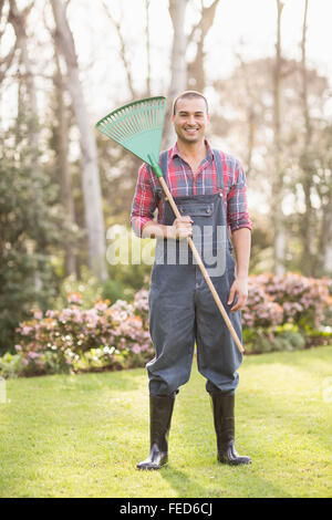 Lächelnde Gärtner hält einen Rechen Stockfoto
