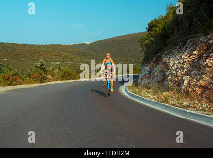 Glückliche Frau Radfahrer mit dem Fahrrad auf einer Bergstraße Stockfoto