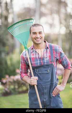 Gärtner-Mann hält eine Harke Stockfoto
