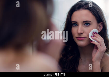 Schöne Brünette, die ihr Gesicht mit Wattepad abwischen Stockfoto
