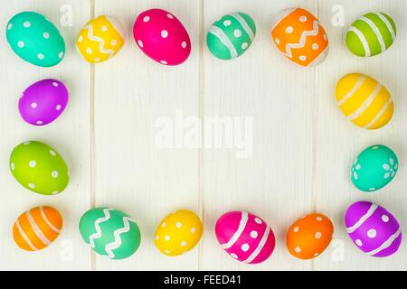 Buntes Osterei Rahmen vor einem weißen Hintergrund Holz Stockfoto