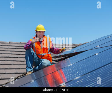 junge Arbeitnehmer, die Überprüfung von Sonnenkollektoren auf dem Hausdach Stockfoto