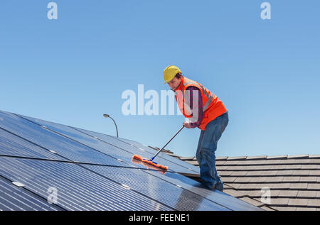 junge Arbeitnehmer Reinigung Solarzellen auf Hausdach Stockfoto