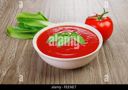 Frische Tomatensuppe in Schüssel auf hölzernen Hintergrund weiß Stockfoto