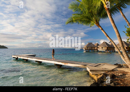 Frau zu Fuß am Steg mit Wasserbungalows des Hotel Le Maitai Bora Bora, Gesellschaftsinseln, Französisch-Polynesien Stockfoto