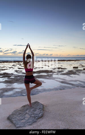 Frau praktizieren Yoga am Strand bei Sonnenaufgang, Fakarava, Tuamotu-Inseln, Französisch-Polynesien Stockfoto