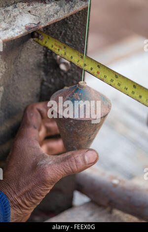 Arbeit-Mann mit einem Senklot für Check-Säule auf Baustelle Stockfoto