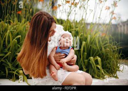 Niedliche glücklich Kleinkind auf liebevolle Mutter Knien sitzen und Lächeln auf den Lippen. Familienspaß. Selektiven Fokus. Stockfoto