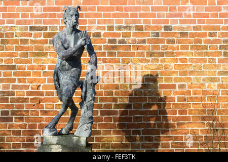 Pan Statue vor einer Ziegelwand mit Schatten Hintergrund in Painswick Rokoko Gardens. Cotswolds, Gloucestershire, UK Stockfoto