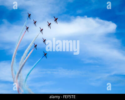 Die roten Pfeile fliegen in Formation mit rot, weiß, und blaue Rauch Wanderwege. Stockfoto