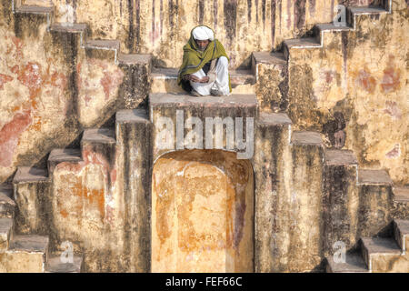 ein Mann sitzt in einem Stufenbrunnen in Jaipur, Rajasthan, Indien, Südasien Stockfoto