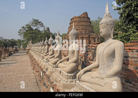 Buddha Statuen unter dem riesigen chedi des Wat Yai Chai Mongkol, Ayutthaya, Thailand, Asien. Stockfoto